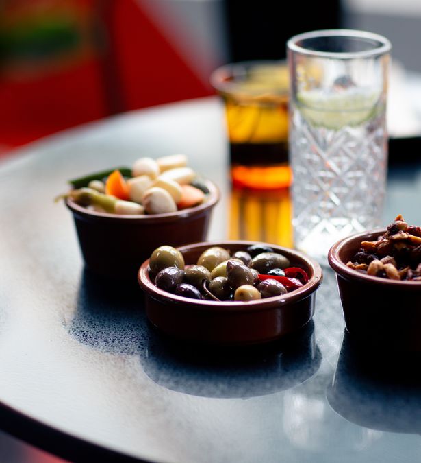 An assortment of small Spanish sharing plates and drinks arranged on a table with a narrow depth of field.